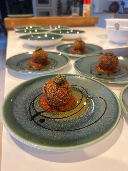 Croquetas con salsa roja en platos de cerámica verde servidas por un chef privado.